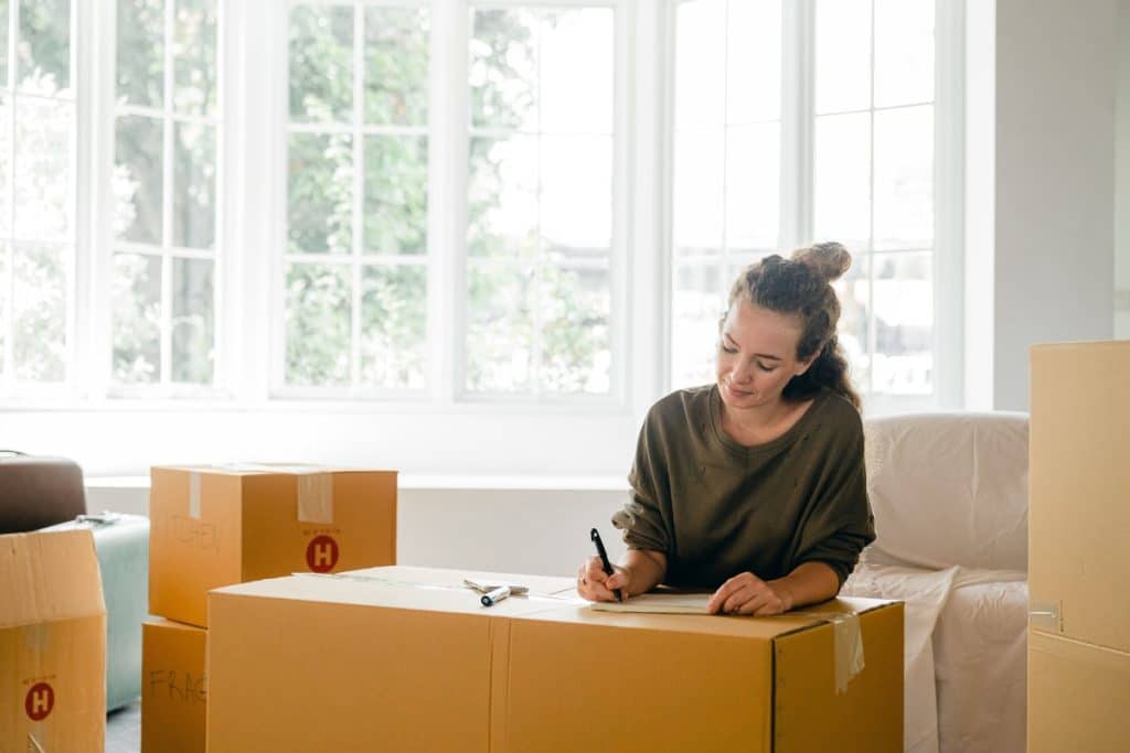 young-women-writing-on-a-cardboard-moving-box